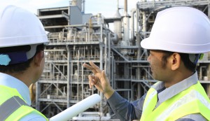 two engineer discussing a new project with large oil refinery background